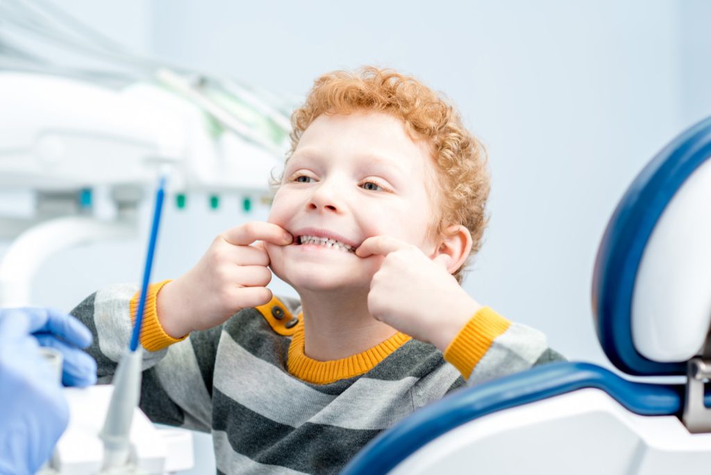 Kind zeigt spielerisch seine Zähne beim Zahnarzt