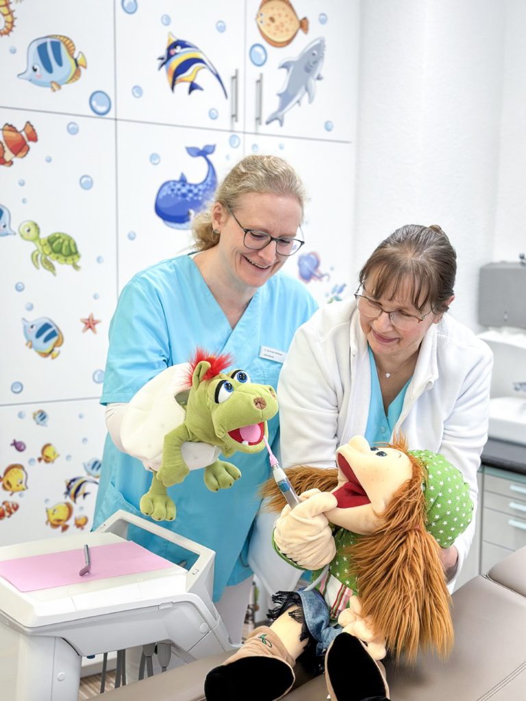 Zahnärztin gemeinsam mit Mitarbeiterin bei der kinderfreundlichen Behandlung