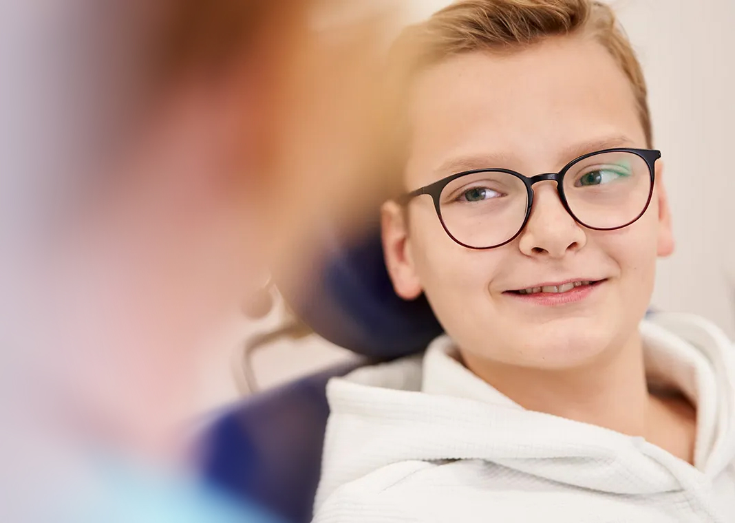 Junge mit Brille entspannt im Zahnarztstuhl