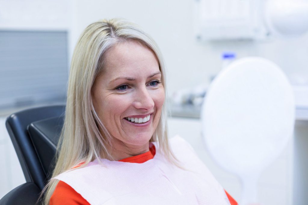 Patientin lächelt nach erfolgreicher Zahnbehandlung