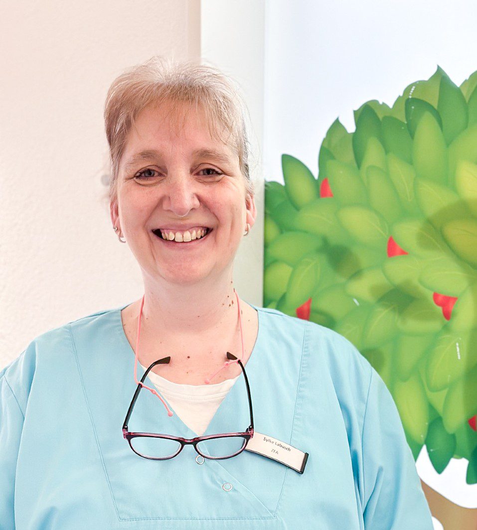 Mitarbeiterin der Zahnarztpraxis im Portrait vor kinderfreundlicher Wandgestaltung