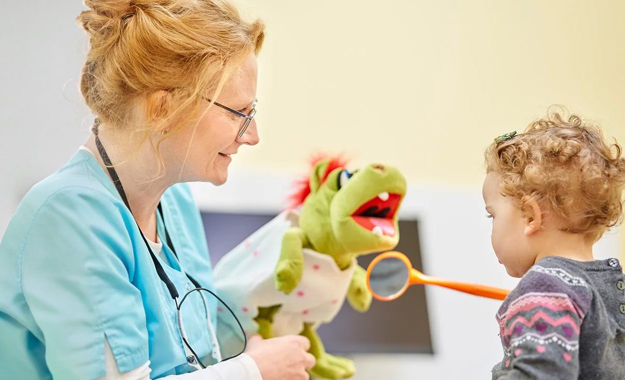 Zahnärztin erklärt Behandlung mit Handpuppe für Kinder