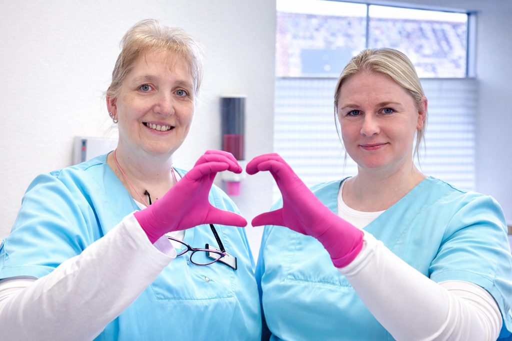 Zahnarzt-Team zeigt Herzsymbol mit Händen in der Praxis