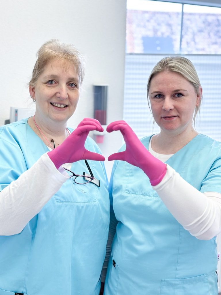 Praxisteam zeigt Herzsymbol für Patientenfreundlichkeit