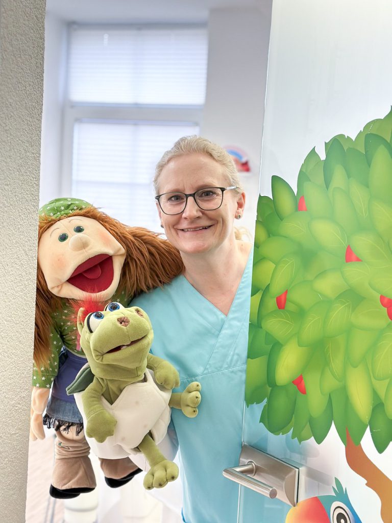 Zahnärztin mit Handpuppen in kinderfreundlicher Zahnarztpraxis
