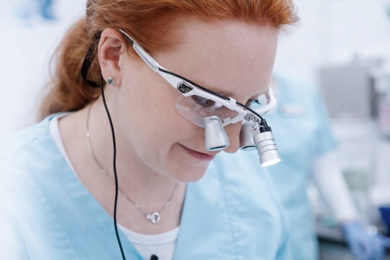 Zahnärztin arbeitet mit Lupenbrille